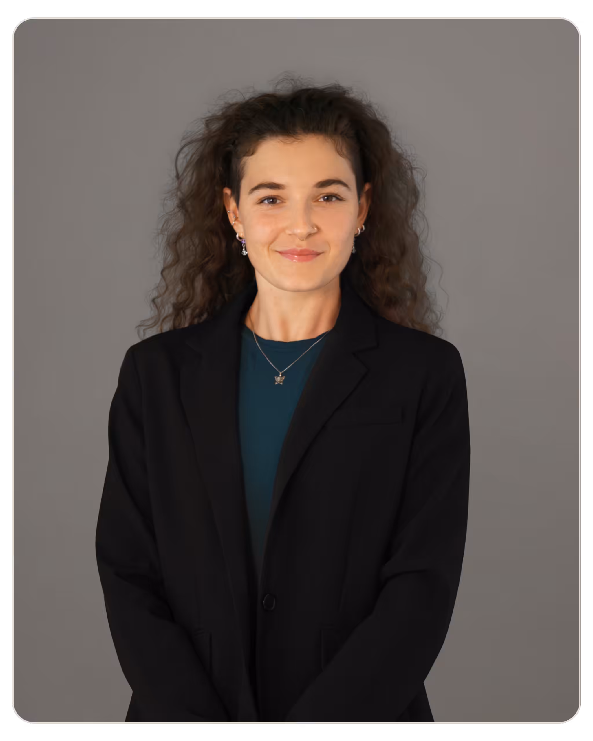 Kandela - Alexandra Giourtzidou MS, RMHCI. Professional woman posing for headshot, smiling, in a black blazer and teal blouse against a gray studio backdrop.