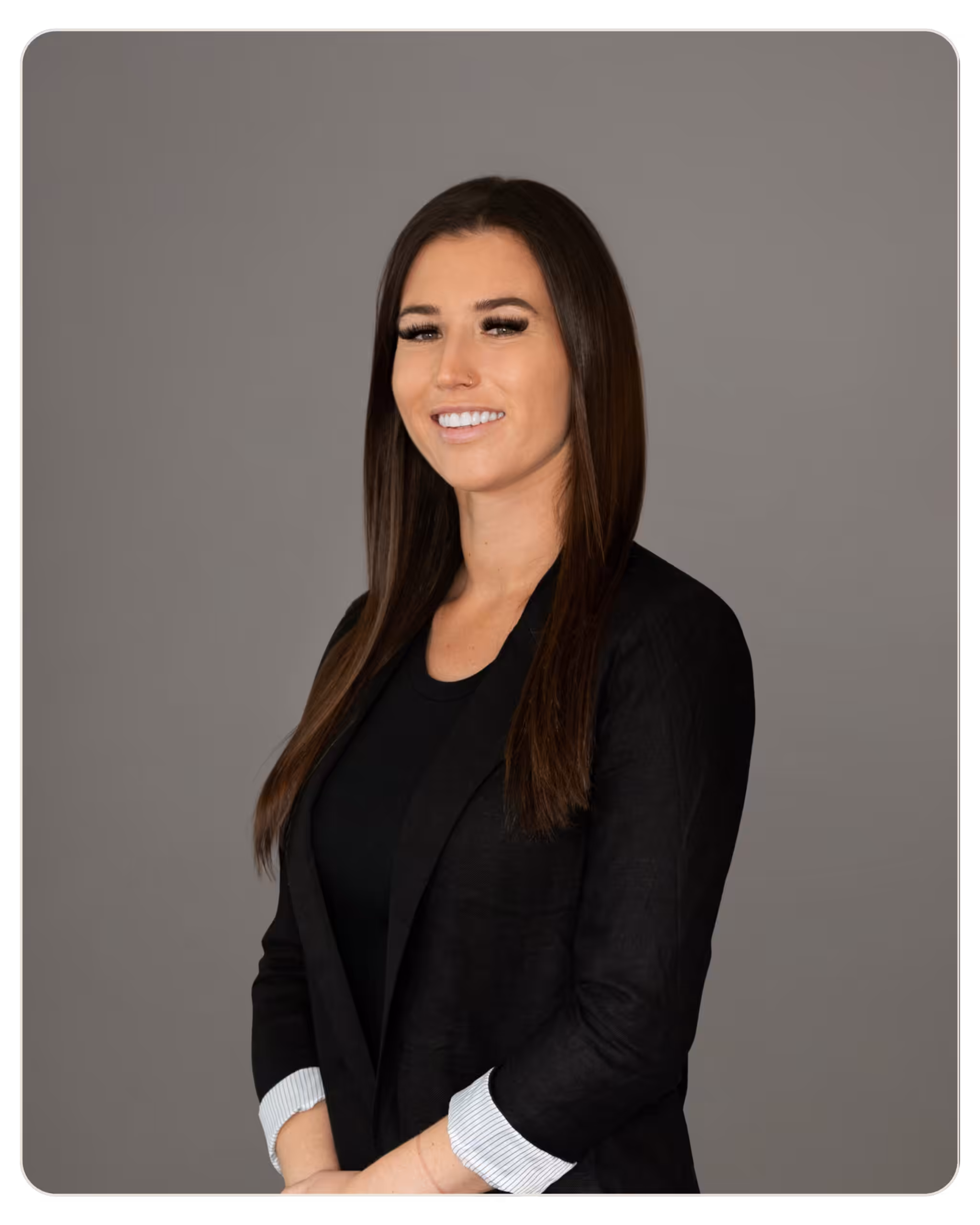 Alexandra Moreno: Recovery Coordinator at Radar. Professional head-and-shoulders portrait: smiling woman with long dark hair in a black blazer against a gray backdrop.