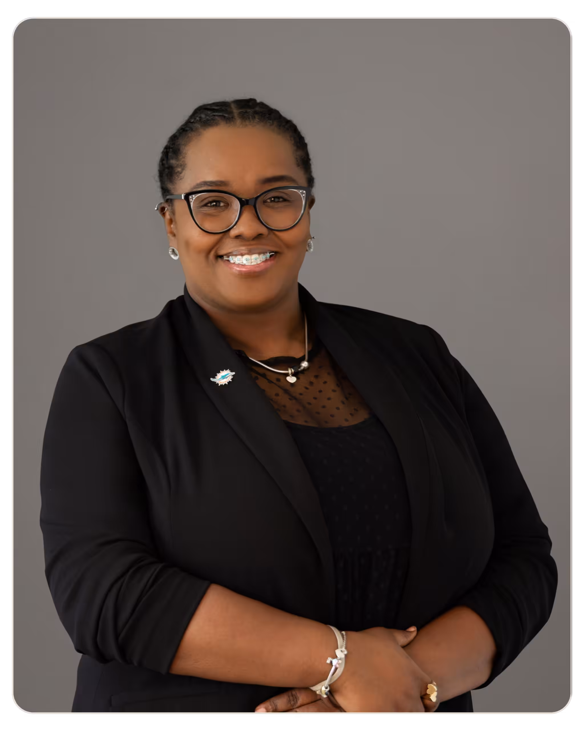 Professional head-and-shoulders portrait of a smiling Black woman in a black blazer and glasses. Professional head-and-shoulders portrait of a smiling Black woman with braided hair, glasses, and a black blazer