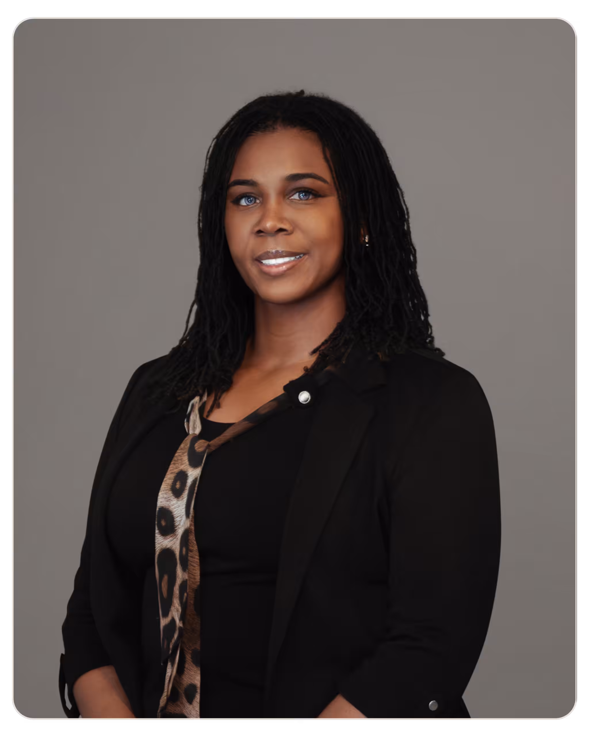 Kizzy Thomas, MSW: Primary Therapist at Beacon. Professional headshot of a smiling Black woman with braided hair, wearing a black blazer against a gray background.