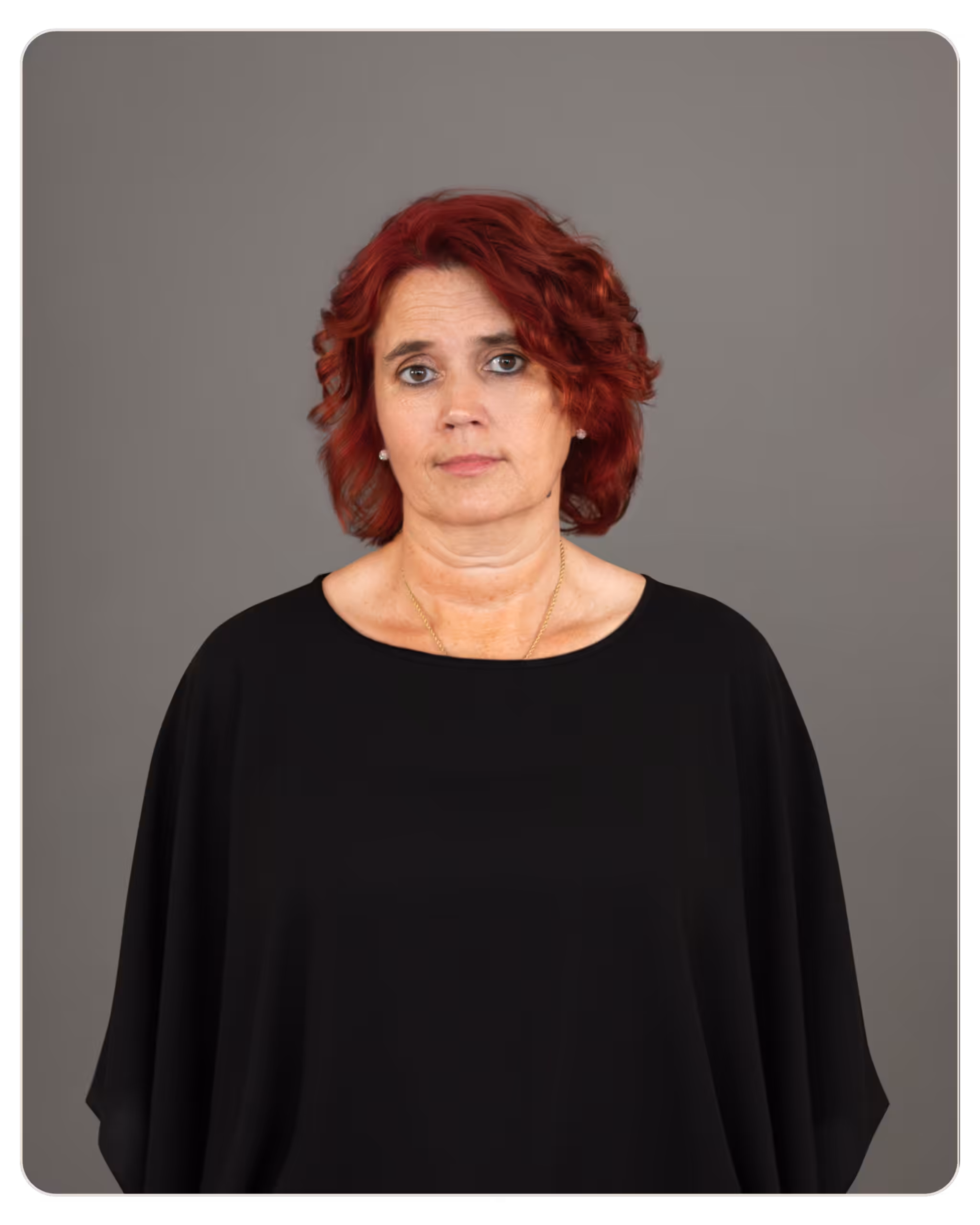 Margie Green, LPN: Director of Nursing at Ember. Portrait of a woman with short red hair wearing a black top, facing the camera with a neutral expression against a gray backdrop.