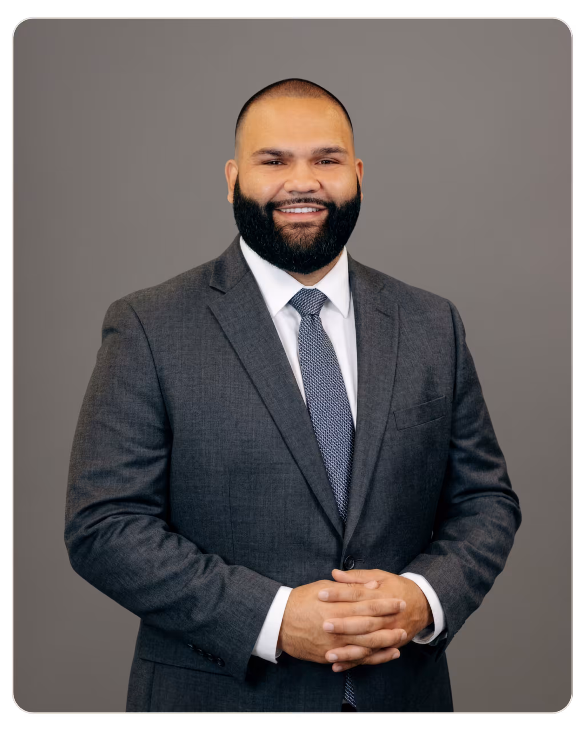 Mario Ulluoa: Executive Director at Aurora. Mario Ulluoa: Executive Director at Aurora. Smiling man in a gray suit with a patterned tie, hands clasped in front against a gray backdrop