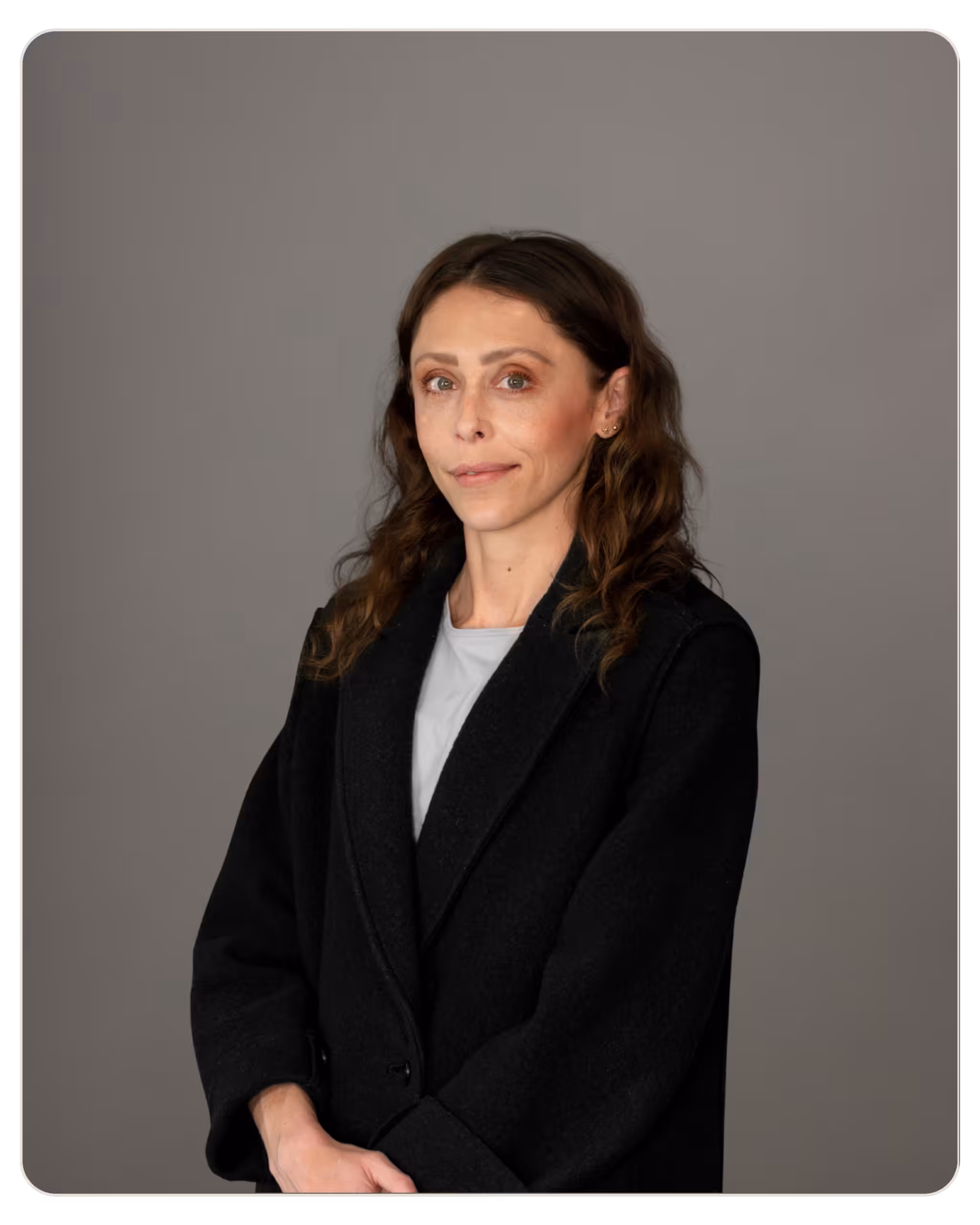 Monica Lee: Patient Care Specialist at Radar. Portrait of a woman with brown hair wearing a black coat over a white top, standing against a gray backdrop.