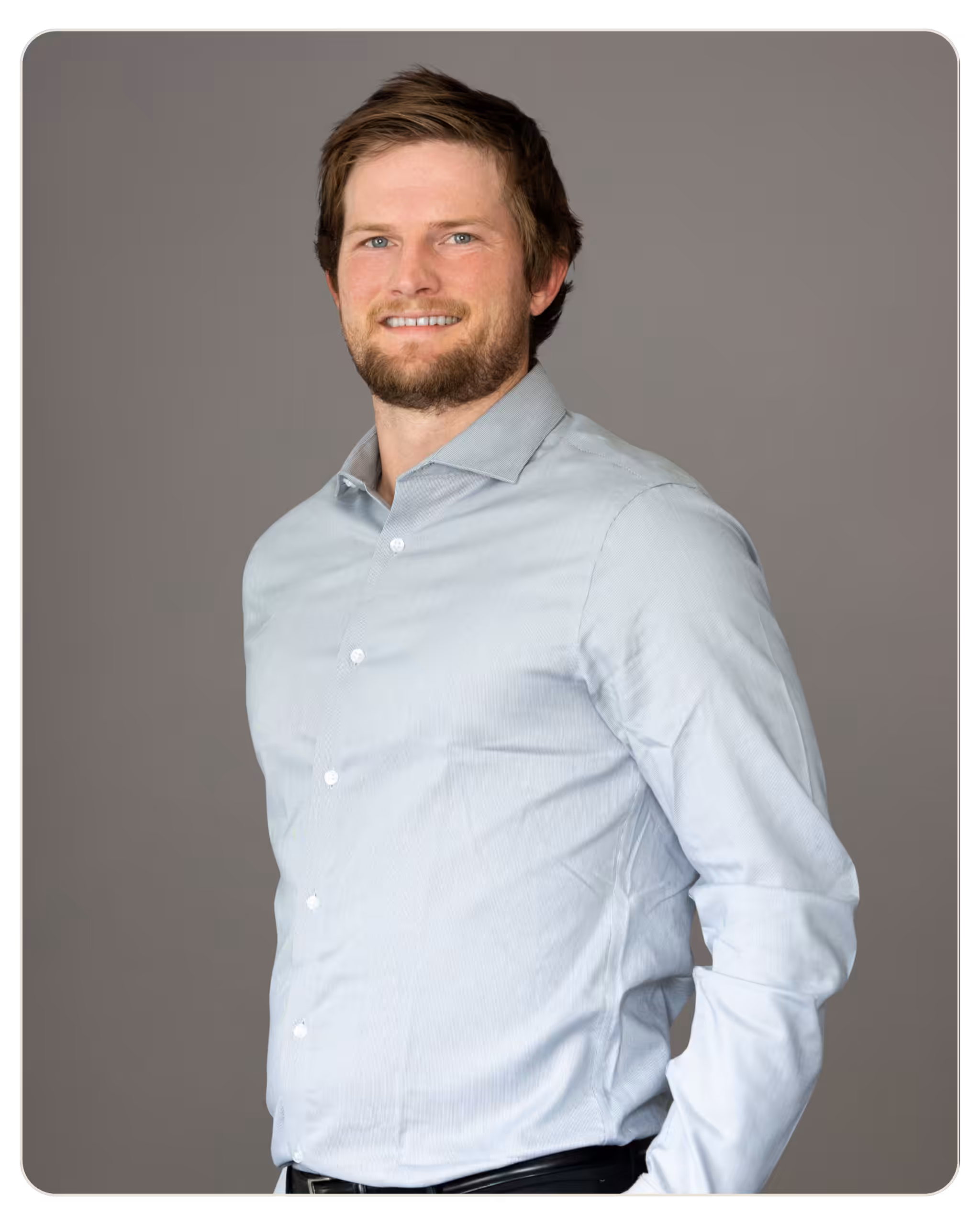 Ryan Weissman: Facility Manager at Radar. Head-and-shoulders portrait of a man in a light blue button-down shirt smiling against a neutral gray backdrop