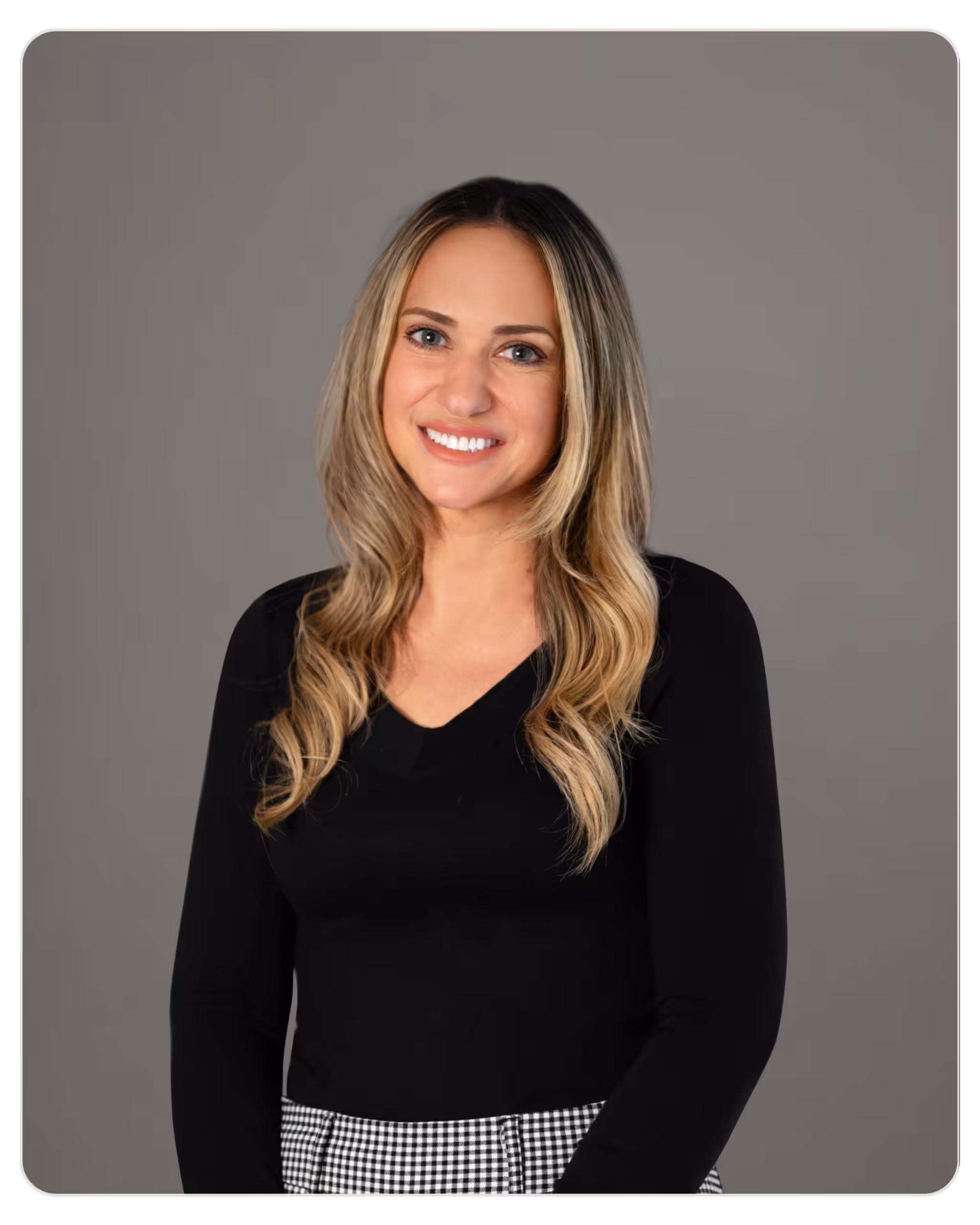 Stephanie Marvin Portrait of a smiling woman with blonde highlights and long hair, wearing a black top, in a neutral studio backdrop.