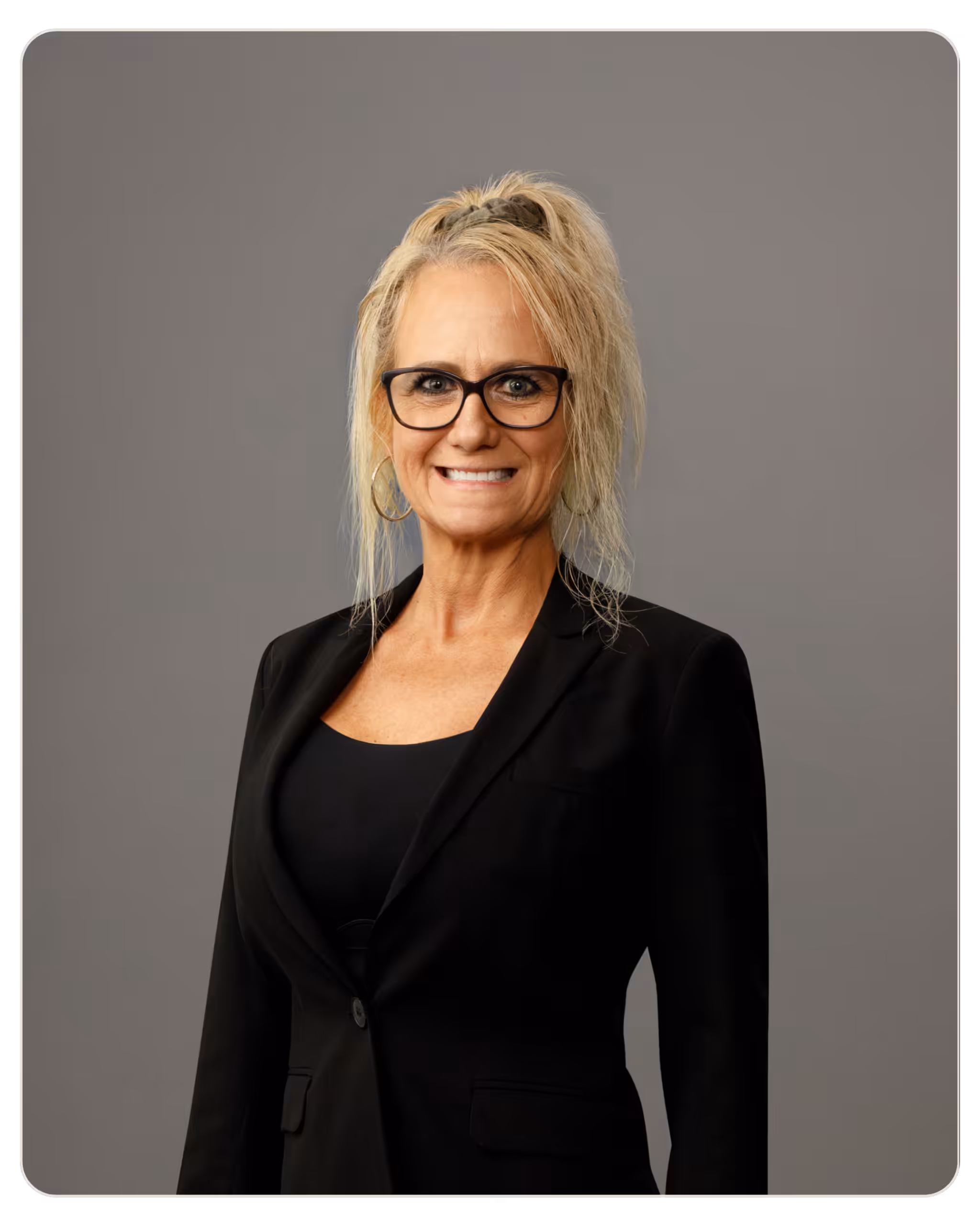 Skylight - Nevalene Moore, RN Smiling blonde woman with dark-framed glasses in a black blazer, against a neutral gray backdrop (professional headshot).]
