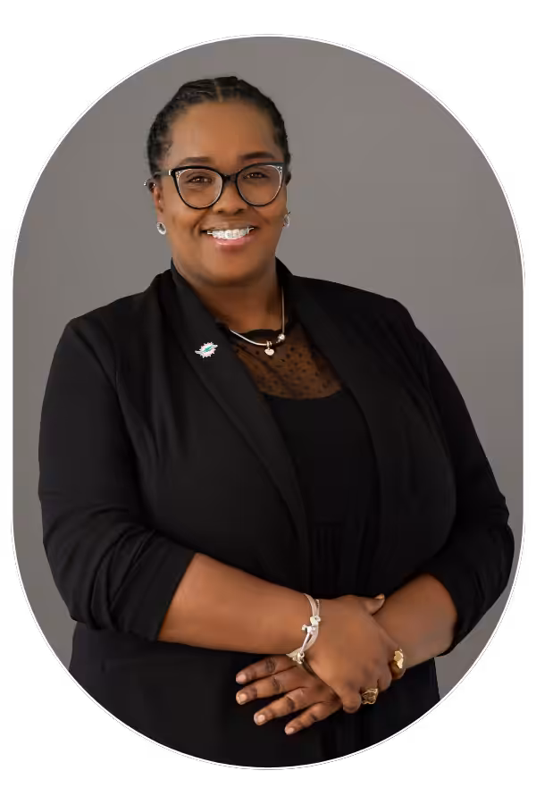 Professional head-and-shoulders portrait of a smiling Black woman in a black blazer and glasses.