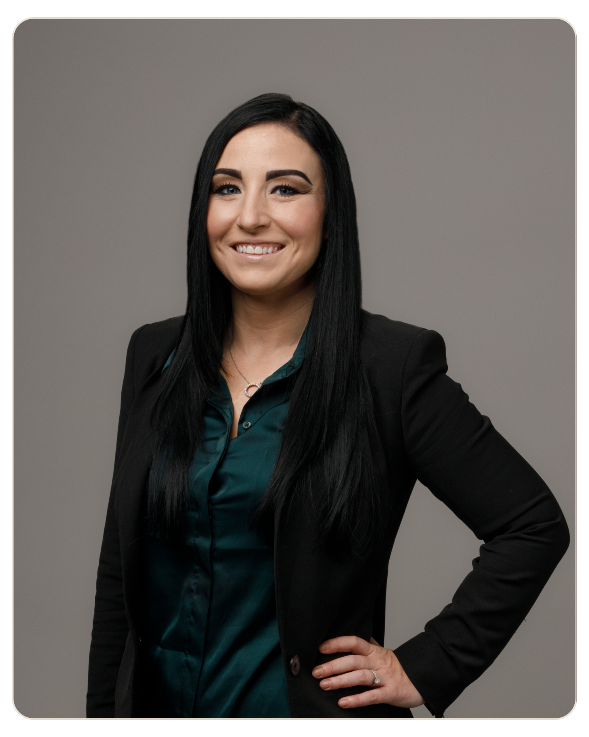 Breanna Walters, MS: Program Director at Daylight. Smiling woman with long black hair in a black blazer and teal blouse, hand on hip against a gray backdrop.