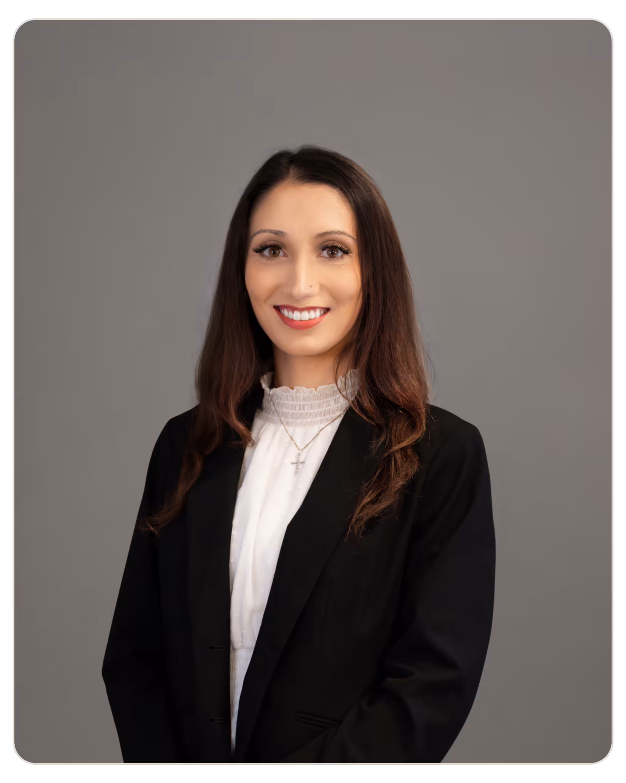 Micaela Shick: Director of Nursing at Prisma. Professional headshot of a smiling woman with long brown hair, wearing a black blazer and white blouse against a gray backdrop.