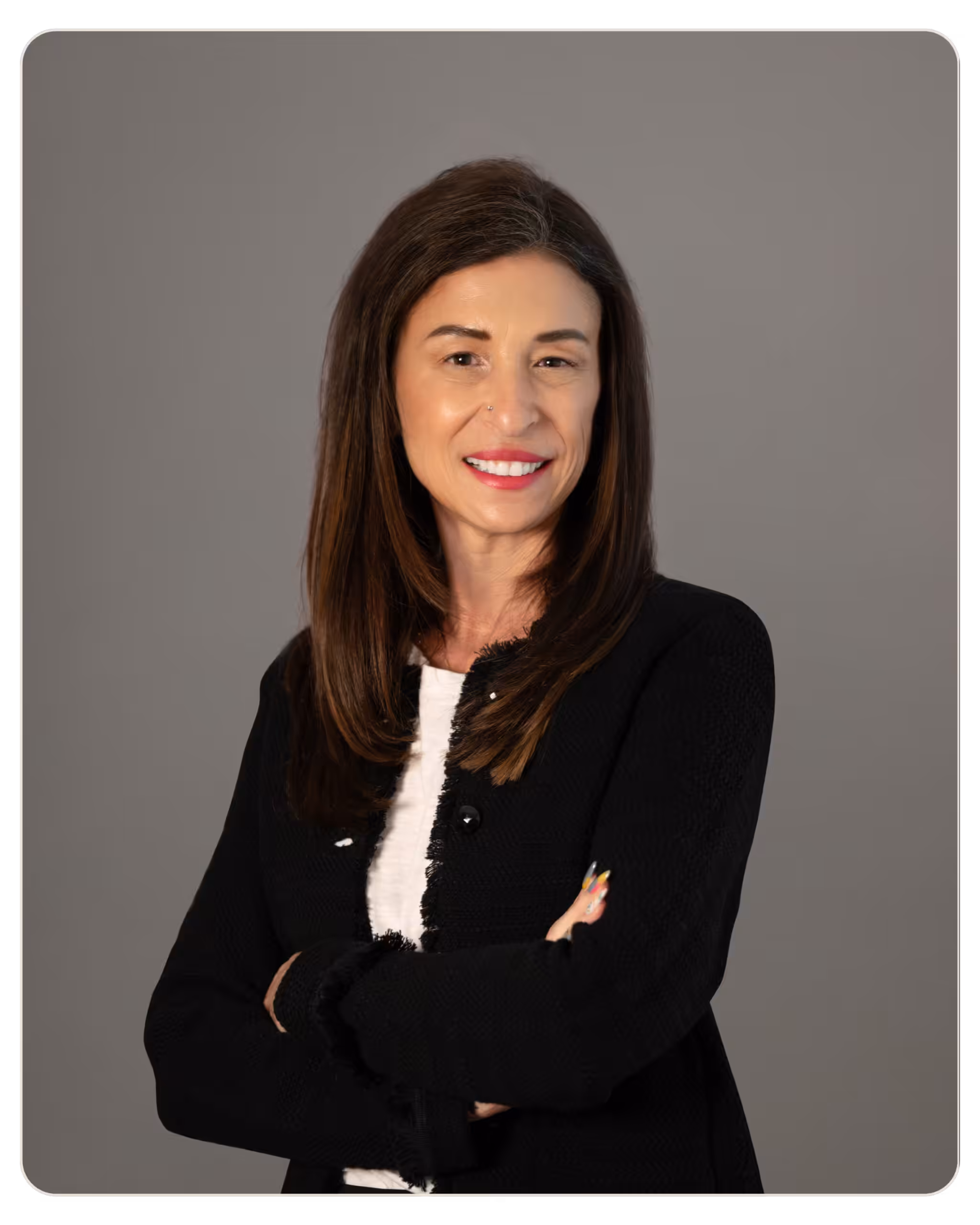 Michele-Rosen, MA, MCAP, CMHP, ICADC. Smiling woman with long brown hair crossing arms against a gray studio backdrop.