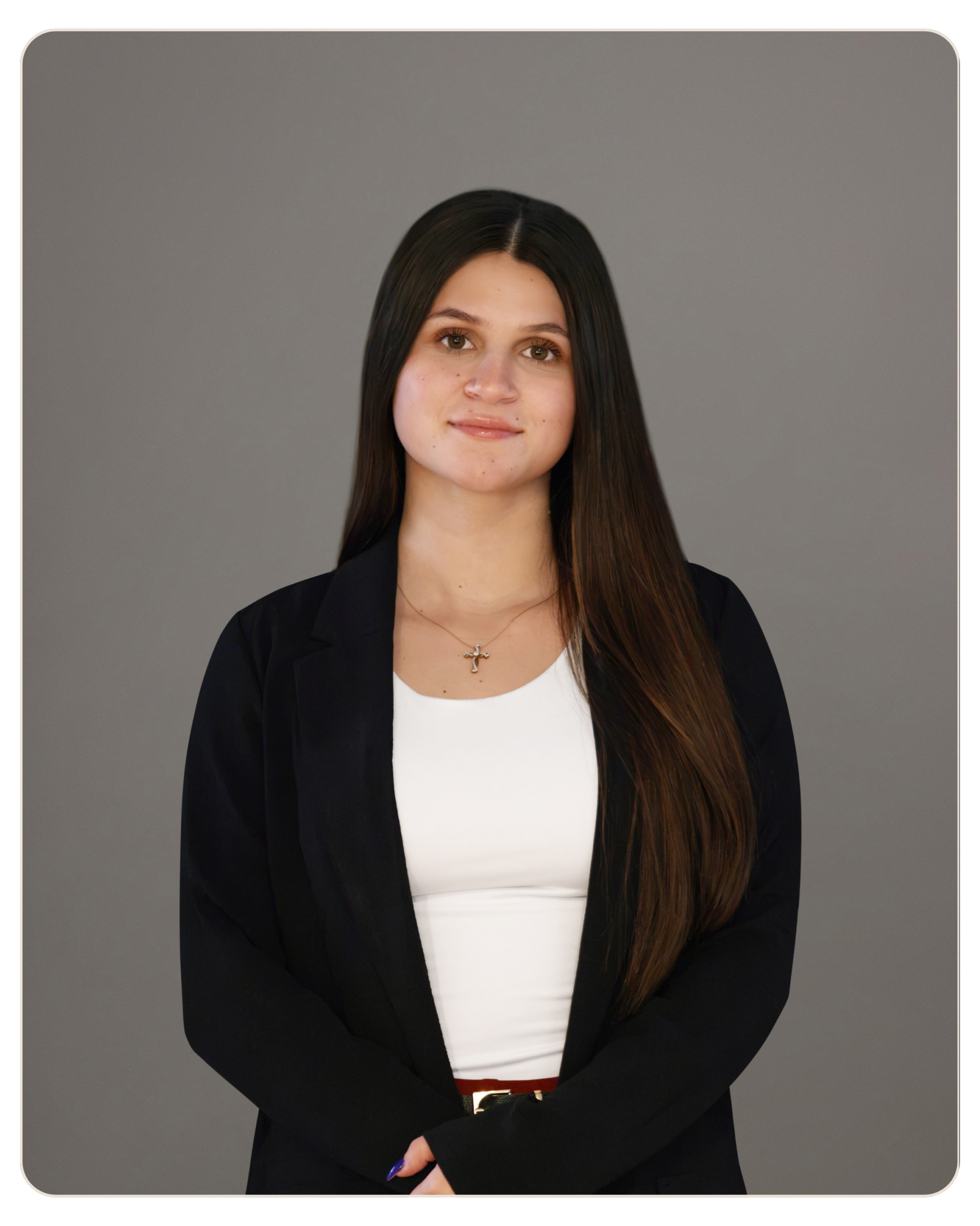 Professional portrait of a young woman with long dark hair, wearing a black blazer and white top, against a neutral gray background. Portrait of a professional-looking woman with long dark hair in a black blazer and white top, standing against a gray studio background.