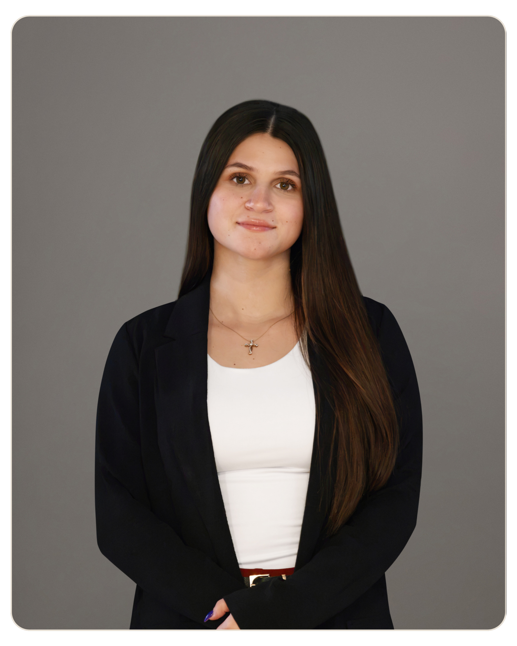 Professional portrait of a young woman with long dark hair, wearing a black blazer and white top, against a neutral gray background. Portrait of a professional-looking woman with long dark hair in a black blazer and white top, standing against a gray studio background.